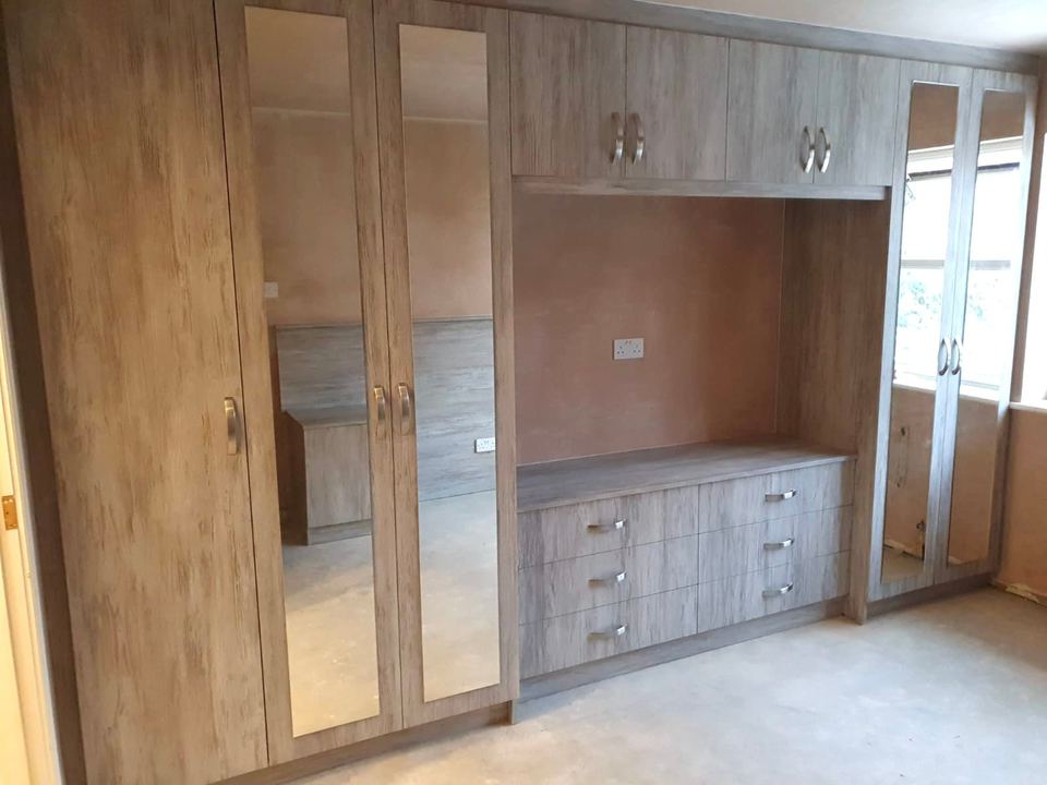 Full-wall fitted bedroom storage with a television recess — finished
