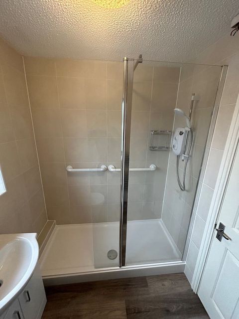 A bath-length low-level shower tray and enclosure fitted where a bath used to be