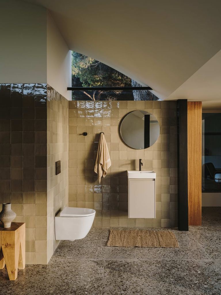 Ona compact unit and round mirror in a green-tiled shower room