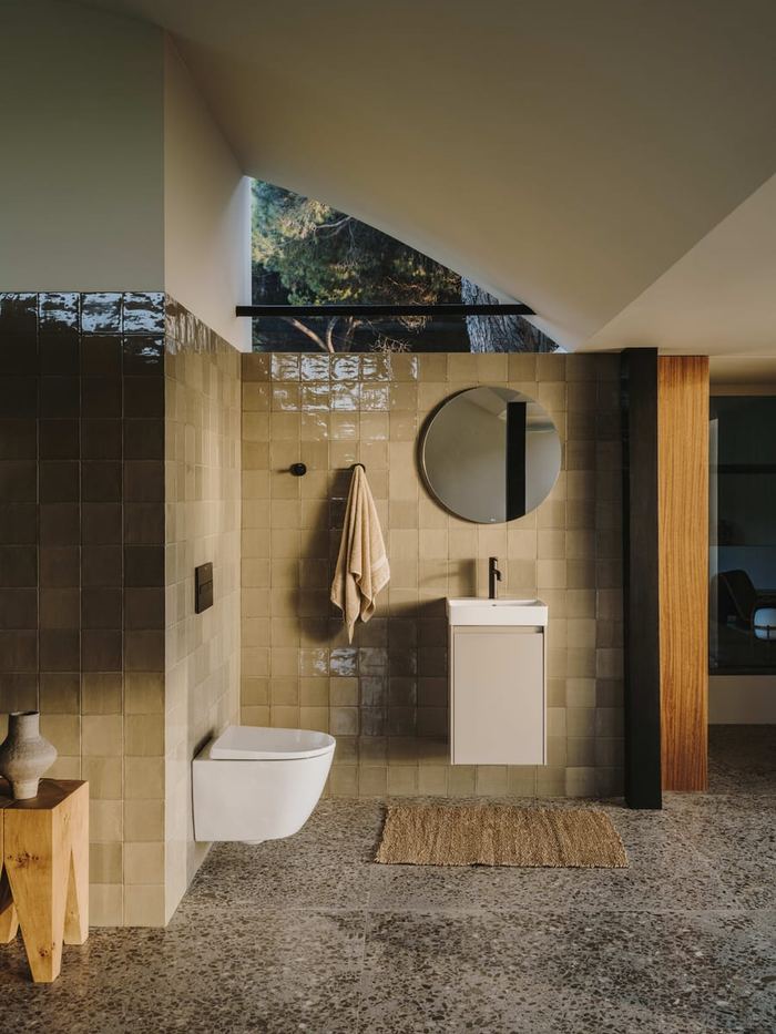 Ona compact unit and round mirror in a green-tiled shower room