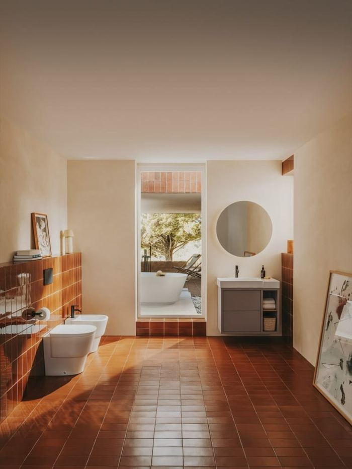 Tura wall-hung unit with a round mirror in a terracotta-floored room