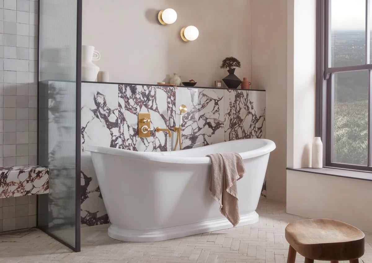 Keswick brassware in Timeless Brushed Brass, with a freestanding bath and marble panelling
