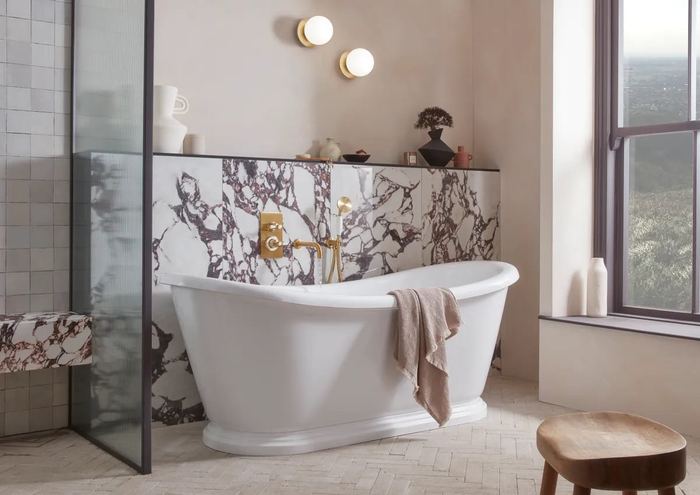 Keswick brassware in Timeless Brushed Brass, with a freestanding bath and marble panelling